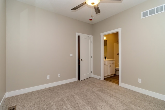 unfurnished bedroom with ceiling fan, light colored carpet, and connected bathroom