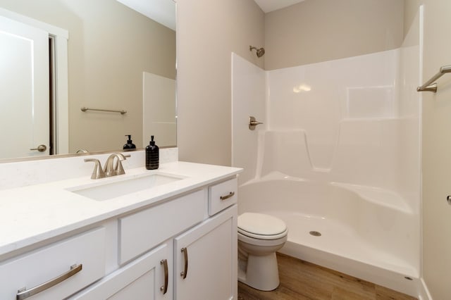 bathroom featuring hardwood / wood-style floors, vanity, toilet, and a shower