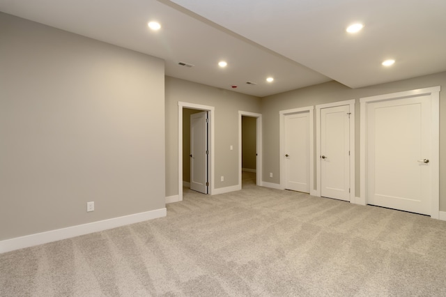 unfurnished bedroom featuring light colored carpet and multiple closets