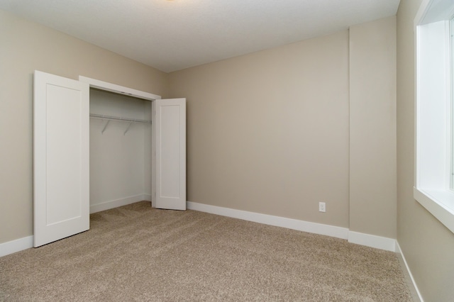 unfurnished bedroom featuring light carpet and a closet