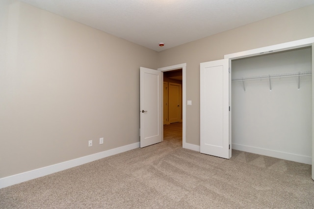 unfurnished bedroom with light colored carpet and a closet