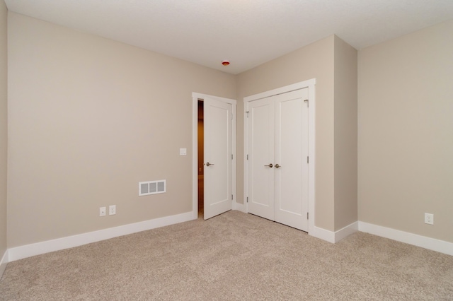 unfurnished bedroom featuring light carpet and a closet