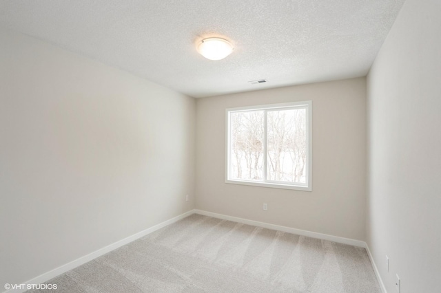 unfurnished room with carpet, visible vents, a textured ceiling, and baseboards