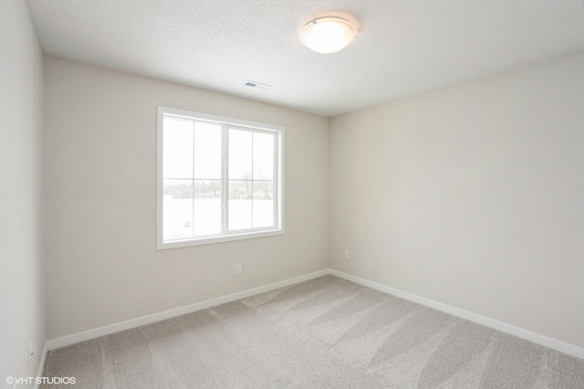 unfurnished room featuring a textured ceiling, carpet floors, visible vents, and baseboards