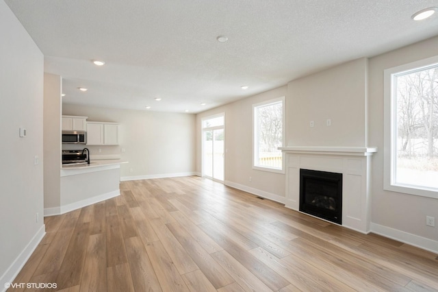 unfurnished living room featuring light wood-style floors, a wealth of natural light, and a fireplace