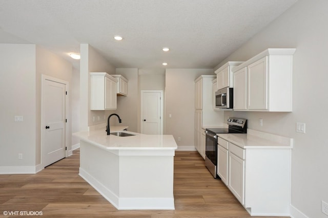 kitchen with light wood finished floors, white cabinetry, stainless steel appliances, and light countertops