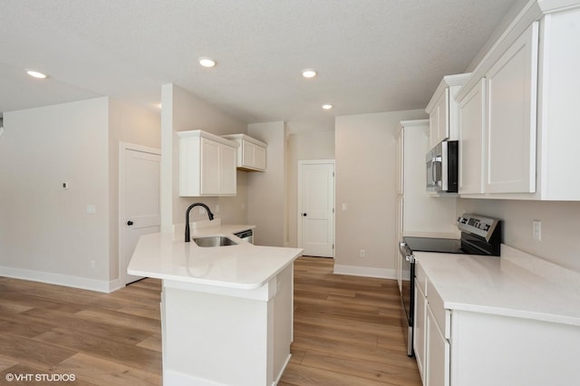 kitchen featuring appliances with stainless steel finishes, light countertops, light wood-type flooring, white cabinetry, and a sink