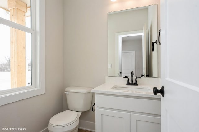 half bathroom featuring baseboards, vanity, and toilet