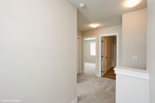 hall featuring light carpet and baseboards