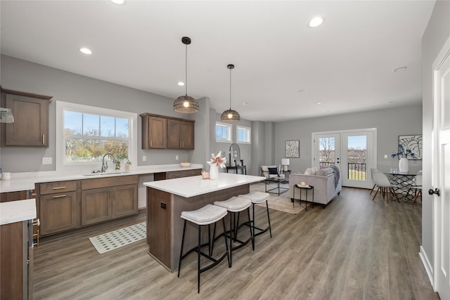 kitchen with sink, a center island, a kitchen breakfast bar, hardwood / wood-style floors, and pendant lighting