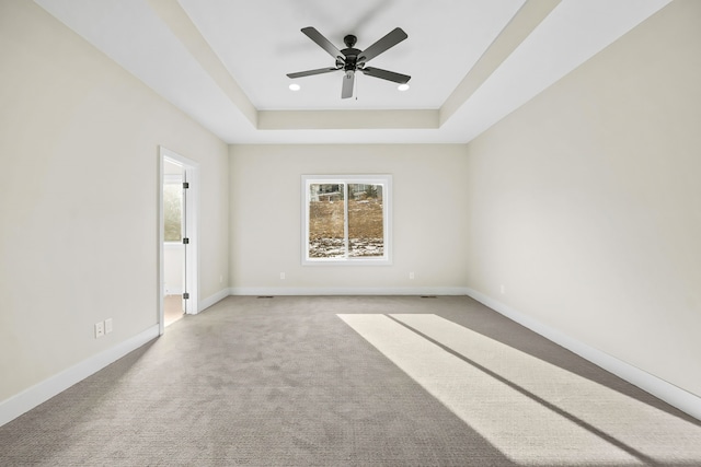 carpeted empty room with ceiling fan and a tray ceiling