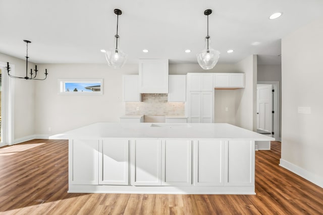 kitchen with white cabinetry, a large island, decorative light fixtures, and light wood-type flooring