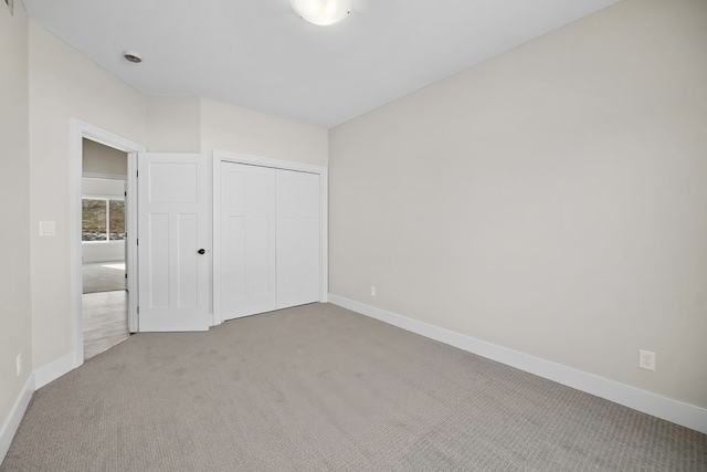 unfurnished bedroom featuring light colored carpet and a closet