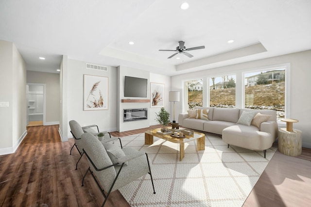 living room with hardwood / wood-style flooring and a raised ceiling