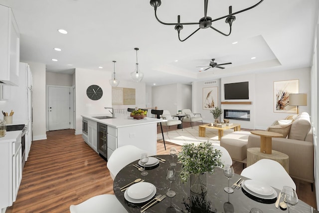 dining space with sink, ceiling fan, dark hardwood / wood-style floors, wine cooler, and a tray ceiling