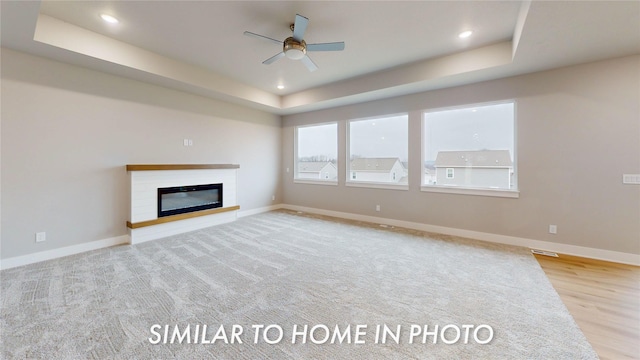 unfurnished living room with a raised ceiling and ceiling fan