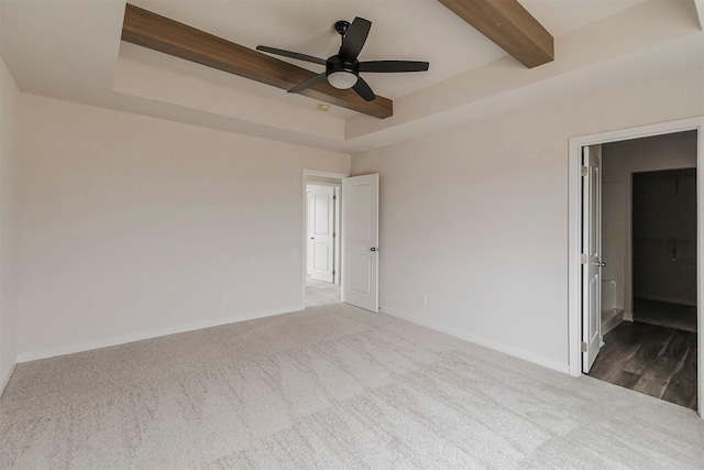 carpeted spare room with a tray ceiling, beam ceiling, and ceiling fan