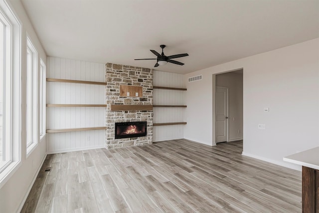 unfurnished living room featuring ceiling fan, a fireplace, and light wood-type flooring