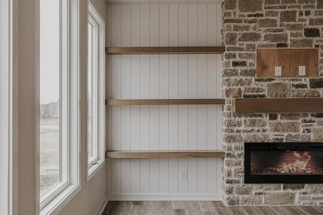 interior details featuring a stone fireplace and wood-type flooring