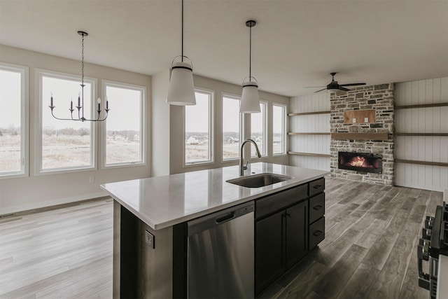 kitchen featuring decorative light fixtures, dishwasher, sink, a center island with sink, and light wood-type flooring