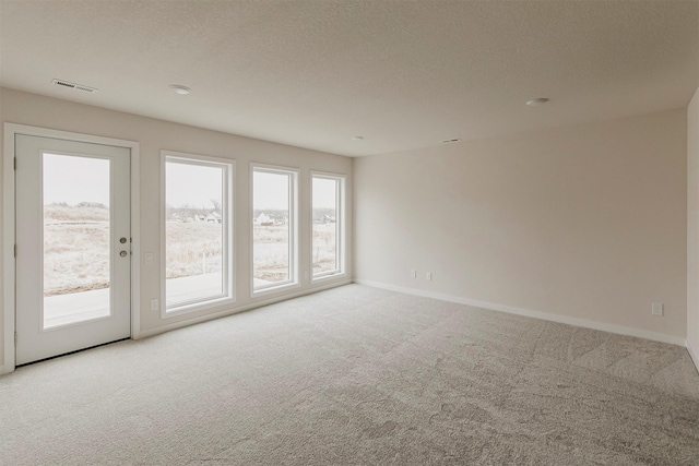 carpeted empty room featuring a textured ceiling