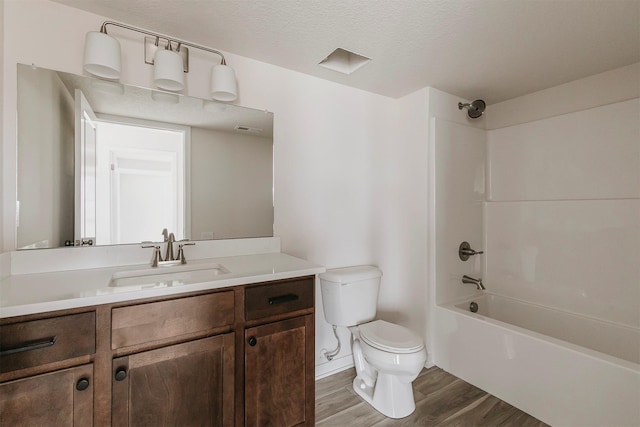 full bathroom with hardwood / wood-style floors, shower / bathing tub combination, vanity, toilet, and a textured ceiling