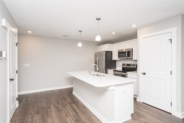 kitchen with stainless steel appliances, hanging light fixtures, dark wood-type flooring, and an island with sink