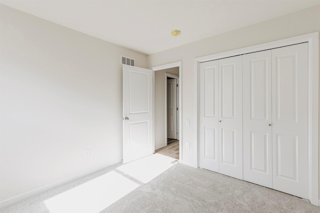 unfurnished bedroom featuring light carpet and a closet