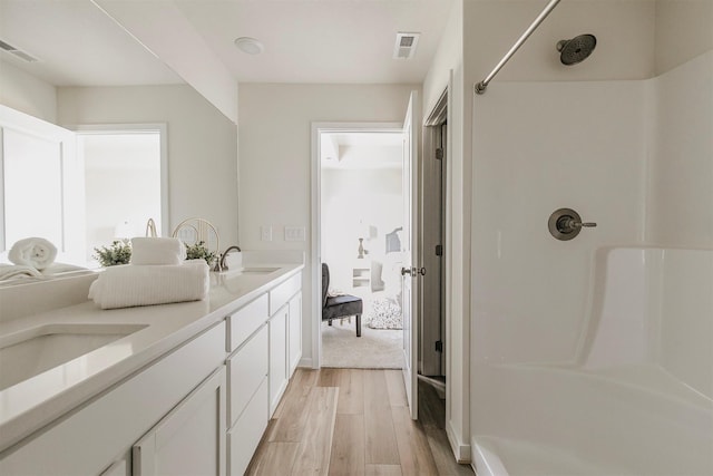 bathroom featuring hardwood / wood-style flooring, vanity, and walk in shower