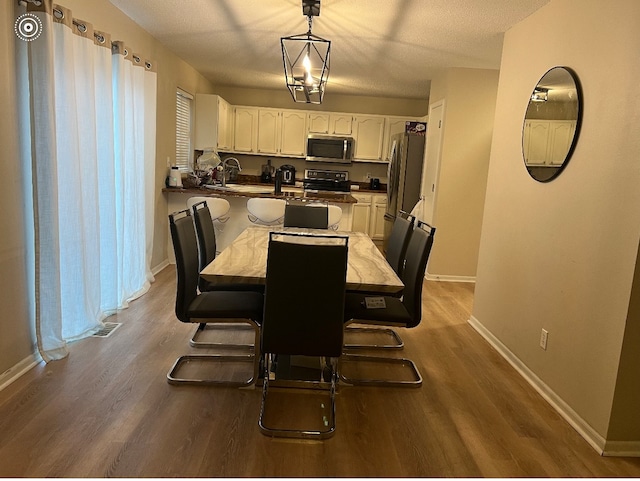 dining space with dark hardwood / wood-style flooring, a textured ceiling, and an inviting chandelier