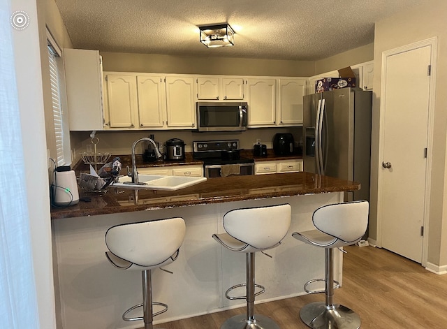 kitchen featuring kitchen peninsula, sink, stainless steel appliances, and light hardwood / wood-style floors