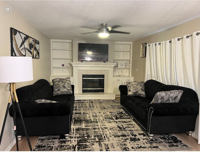 living room featuring a fireplace, a textured ceiling, dark hardwood / wood-style floors, and ceiling fan