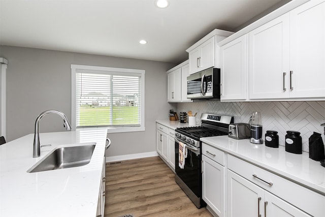 kitchen featuring white cabinetry, sink, light hardwood / wood-style floors, and appliances with stainless steel finishes