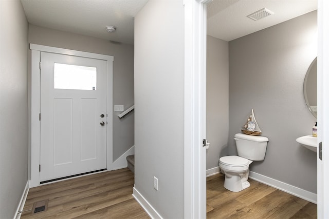 bathroom featuring hardwood / wood-style flooring, toilet, and a textured ceiling