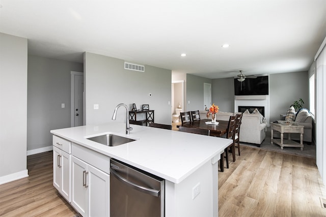 kitchen featuring a center island with sink, sink, stainless steel dishwasher, light wood-type flooring, and white cabinetry