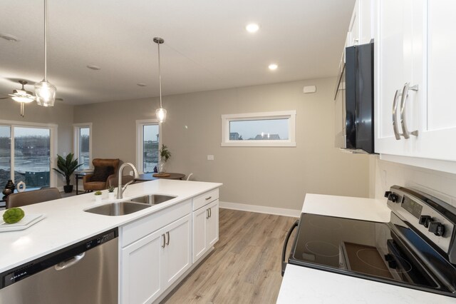 kitchen featuring sink, hanging light fixtures, electric range, stainless steel dishwasher, and light wood-type flooring