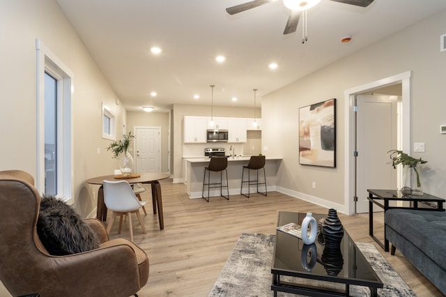 living room with ceiling fan and light wood-type flooring