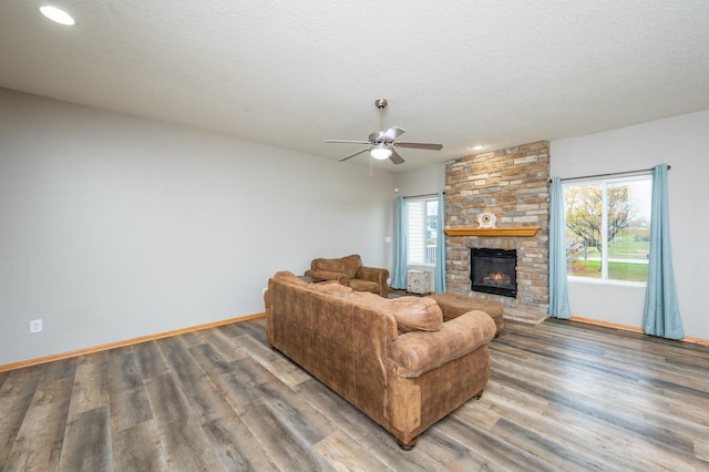 living room with ceiling fan, a fireplace, hardwood / wood-style floors, and a textured ceiling