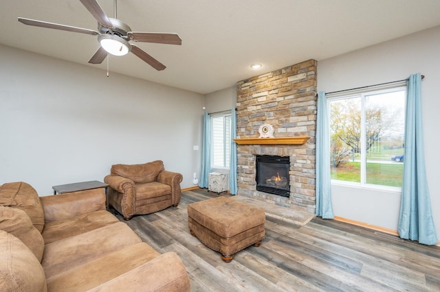 living room with a wealth of natural light, a fireplace, ceiling fan, and hardwood / wood-style flooring