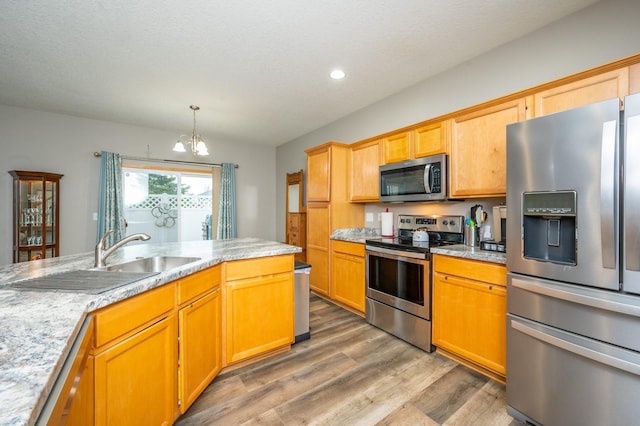 kitchen with an inviting chandelier, sink, hardwood / wood-style flooring, appliances with stainless steel finishes, and decorative light fixtures