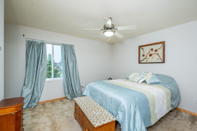 bedroom with ceiling fan, light colored carpet, and a textured ceiling