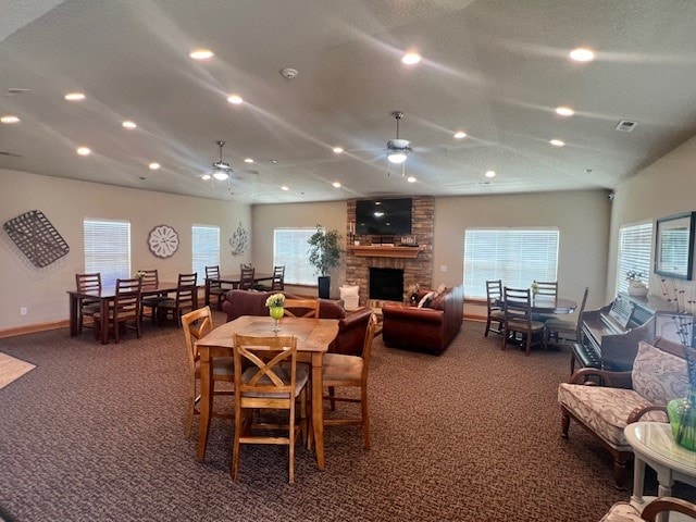 carpeted dining area with a fireplace and ceiling fan