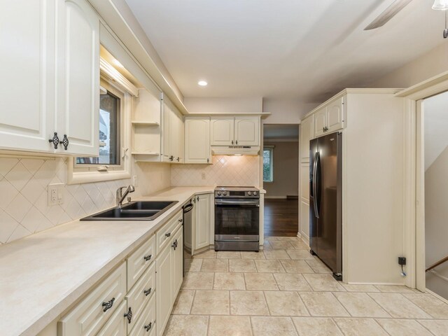 kitchen with stainless steel appliances, light tile patterned flooring, decorative backsplash, and sink