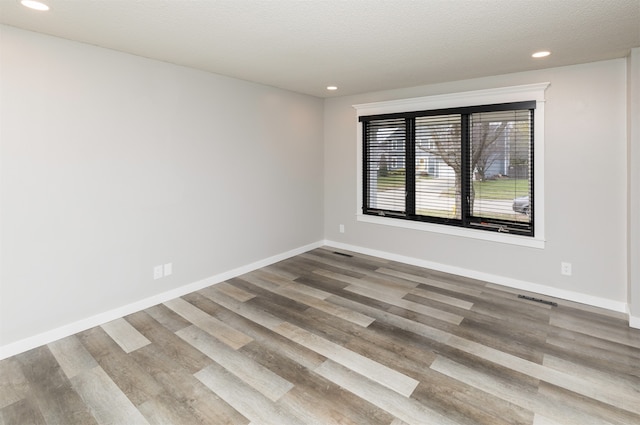 spare room featuring hardwood / wood-style flooring and a textured ceiling