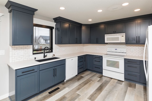 kitchen featuring backsplash, sink, white appliances, and light wood-type flooring