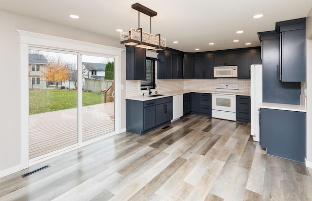6562 Center St, West Des Moines, IA 50266 - kitchen featuring white appliances, backsplash, light countertops, light wood finished floors, and recessed lighting