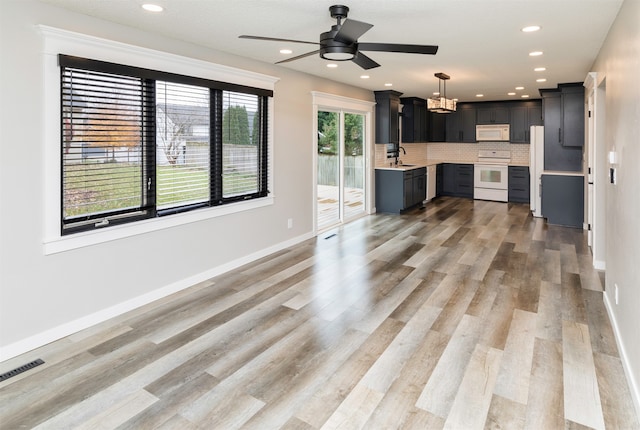 unfurnished living room with light hardwood / wood-style floors, ceiling fan, and sink