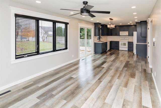 6562 Center St, West Des Moines, IA 50266 - unfurnished living room with ceiling fan, light wood finished floors, baseboards, recessed lighting, and a chandelier