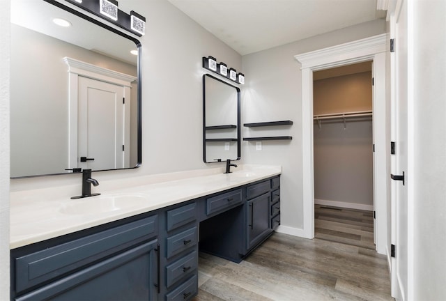 6562 Center St, West Des Moines, IA 50266 - bathroom with wood finished floors, double vanity, a walk in closet, baseboards, and recessed lighting