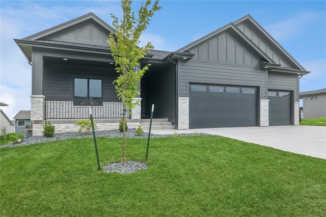 view of front of property featuring covered porch, a garage, and a front lawn